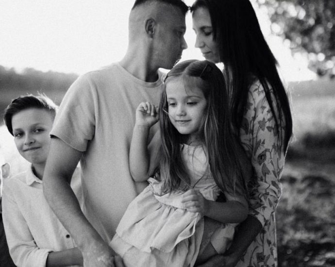 A serene black and white portrait of a family standing by a lake.