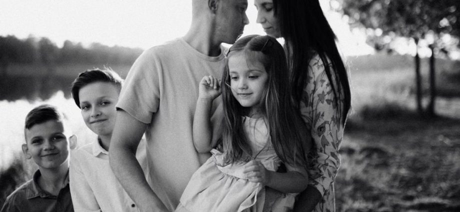 A serene black and white portrait of a family standing by a lake.